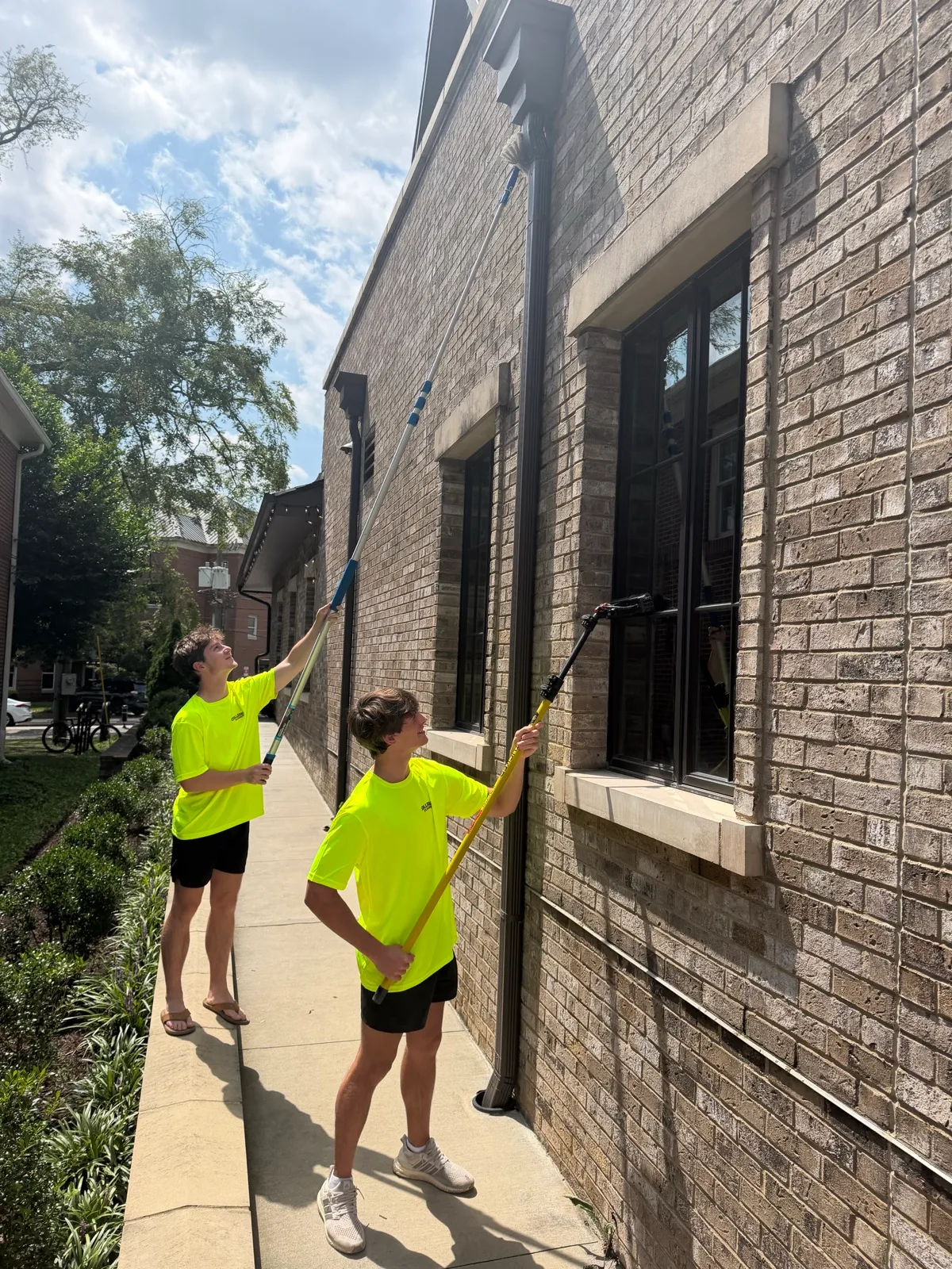 Collegiate Cleaners team cleaning upper windows with water-fed poles